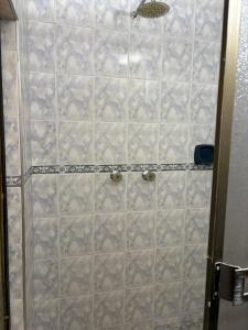 a shower with a beige tiled wall at Hotel Romanza in Bogotá