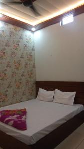 a bed in a bedroom with a floral wallpaper at OM DAYAMA Please in Khātu