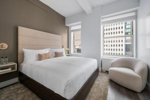 a bedroom with a large white bed and a chair at 17John Residences in New York +210 photos
