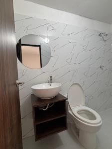 a bathroom with a sink and a toilet and a mirror at El Encanto in Valledupar