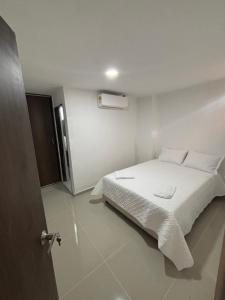 a bedroom with a white bed with white sheets at El Encanto in Valledupar