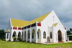 a large white church with a yellow roof at Vunakavika House - Village Stay in Nadi