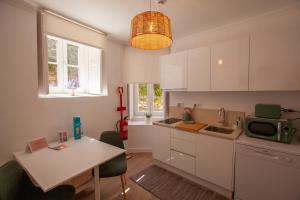 a kitchen with white cabinets and a table with a microwave at Santos da Vila in Sintra
