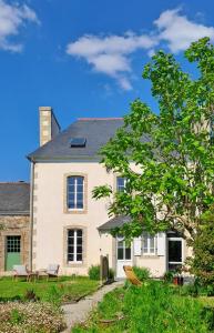 a large white house with benches in front of it at Ty Palms - Maison d'hôtes in Plomodiern