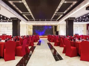 a conference room with red chairs and a screen at Novotel Daqing Haofang in Daqing +85 photos