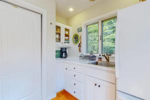 a kitchen with white cabinets and a sink and a window at Nana's Rear Treehouse in West Tisbury