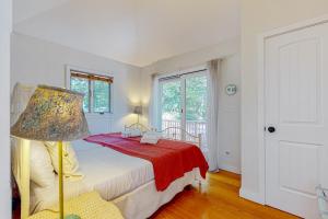 a bedroom with a bed with a lamp and a window at Nana's Rear Treehouse in West Tisbury