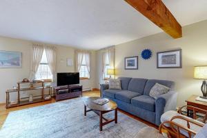 a living room with a blue couch and a tv at Serene Cape Escape in Wellfleet