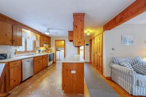 a kitchen with wooden cabinets and a couch in it at Serene Cape Escape in Wellfleet