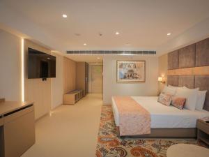 a large hotel room with a bed and a television at Grand Mercure Vadodara Surya Palace in Vadodara