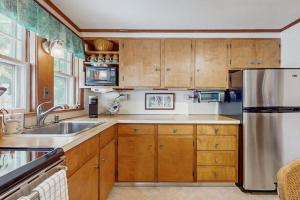 a kitchen with wooden cabinets and a stainless steel refrigerator at Mermaid Cottage in Falmouth
