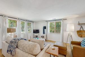 a living room with a couch and chairs and windows at Miles Away in South Dennis