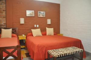a bedroom with two beds and a bench in it at Termas Del Sol in Termas de Río Hondo +52 photos