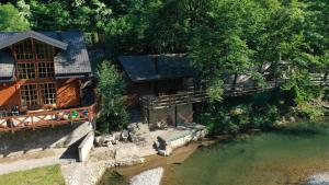 a house with a bridge next to a river at Rzav, ti i ja. in Arilje