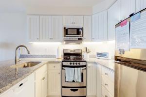a white kitchen with a stove and a microwave at Bayside Beauty in Truro
