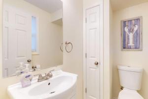 a bathroom with a sink and a toilet and a mirror at Bayside Beauty in Truro