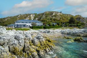 a building on a hill next to a body of water at The Pier Hotel in Kaikoura