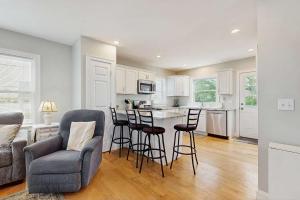 a kitchen with bar stools and a kitchen with white cabinets at Bella Luna in Falmouth