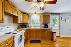 a kitchen with wooden cabinets and a ceiling fan at Winthrop Cottage in Oak Bluffs