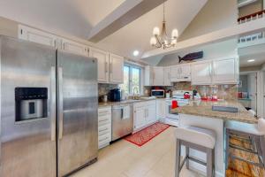 a kitchen with white cabinets and a stainless steel refrigerator at Sit Back & Relax in Eastham +23 photos