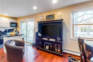 a living room with a flat screen tv and a kitchen at Brewster House in Oak Bluffs