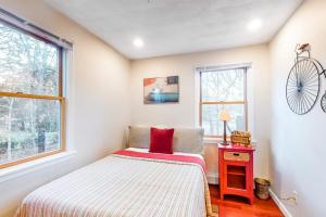 a small bedroom with a bed and a nightstand and two windows at Brewster House in Oak Bluffs +17 photos