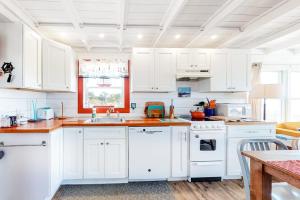a white kitchen with white cabinets and a sink at Dunes Edge in Wellfleet