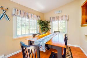 a dining room with a wooden table and two windows at Mattakeese Villa in Yarmouth