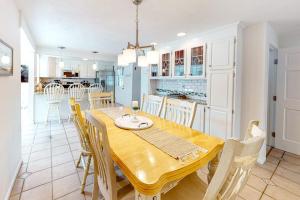 a dining room and kitchen with a wooden table and chairs at Sea You Later in West Yarmouth