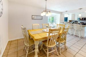 a dining room and kitchen with a wooden table and chairs at Sea You Later in West Yarmouth