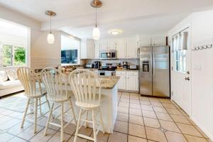 a kitchen with white cabinets and a table and chairs at Sea You Later in West Yarmouth +37 photos