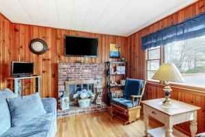 a living room with a fireplace and a tv at Anchors Await in South Yarmouth