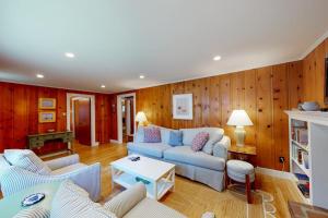 a living room with a blue couch and wooden walls at Sweet Victory in Harwich Port