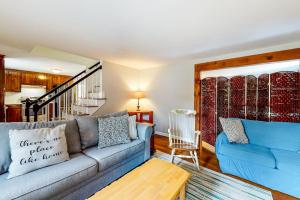 a living room with a blue couch and a staircase at Dream Dennis Getaway in Dennis