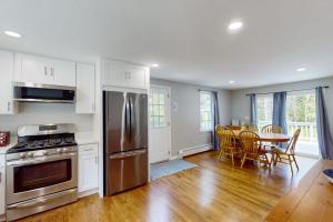 a kitchen with stainless steel appliances and a table with chairs at Dream Dennis Getaway in Dennis