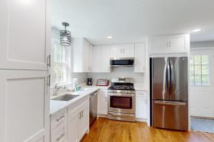 a kitchen with white cabinets and a stainless steel refrigerator at Dream Dennis Getaway in Dennis +16 photos