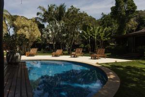 a swimming pool with benches and a yard with trees at Villa Cozy - Pousada Boutique in Arraial d'Ajuda +21 photos