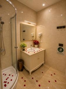 a bathroom with a sink and shower with roses on the floor at Majestik Hanoi Hotel in Hanoi +34 photos