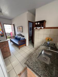a kitchen and living room with a sink and a couch at Casa quadra praia Jacaraipe! in Jacaraípe