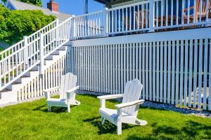 two white chairs sitting in the grass next to a staircase at Barnstable Harbor Home in Barnstable