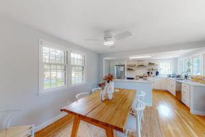 a white kitchen with a wooden table and chairs at New England Getaway in Dennis