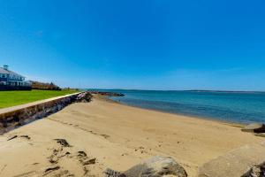a beach with a retaining wall and the ocean at Adventures on Buzzards Bay in Bourne