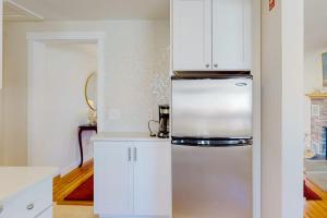 a kitchen with white cabinets and a refrigerator at Adventures on Buzzards Bay in Bourne