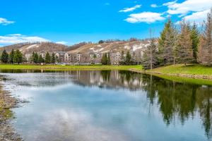 a lake with trees and a building in the background at Boyne Mountain Getaway in Boyne Falls