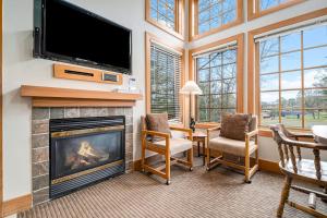 a living room with a fireplace and a flat screen tv at Boyne Mountain Getaway in Boyne Falls