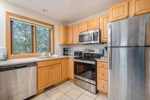 a kitchen with wooden cabinets and a stainless steel refrigerator at Boyne Mountain Getaway in Boyne Falls +32 photos