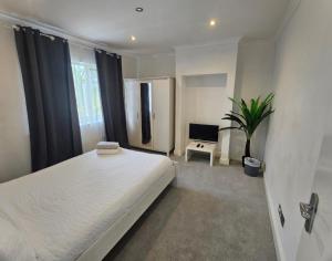 a bedroom with a white bed and a potted plant at Mirandas Place in Gillingham