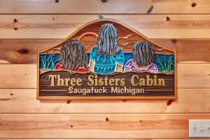 a sign for three sisters cabin on a wooden wall at Kingfisher Cove Cabin 28 in Saugatuck