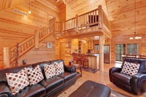 a living room with a leather couch and a staircase at Kingfisher Cove Cabin 28 in Saugatuck +34 photos