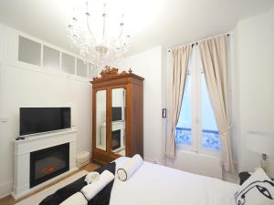 a white bedroom with a chandelier and a fireplace at NOUVEAUTE JUILLET 2026 Le BALCON DE L OPERA in Vichy